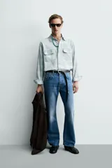 Camisa de algodón con efecto lavado, diseño a cuadros en tonos celestes y beige, cuello solapa, manga larga con puños abotonados y bolsillos frontales con solapa.