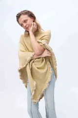 Chal de punto color dorado con acabado en lurex y terminaciones artesanales con volados en los bordes.