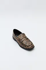 Mocasín de cuero sintético negro con punta cuadrada, detalle de costuras visibles en la capellada y taco bajo.