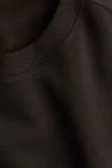 Buzo de tejido liso color marrón oscuro, con cuello redondo, hombros caídos y puños y bajo acanalados.
