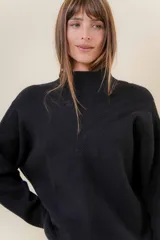 Sweater tejido de punto color negro, con cuello alto y diseño en relieve tipo chevron en forma de V en el frente. Presenta un calce relajado y holgado con terminaciones acanaladas en puños y ruedo.