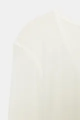 Camiseta blanca de manga larga, corte slim fit y escote pico pronunciado. Tejido ligero y ligeramente transparente con textura acanalada.