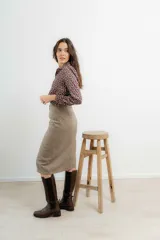 Falda midi de tiro alto confeccionada en tejido tweed con patrón de espiga en tono marrón. Presenta un diseño recto y cierre frontal con botones.