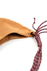 Bolso tipo morral color marrón de diseño curvo, con manija de cuerda trenzada en tonos burdeos y detalles de nudos en los extremos.