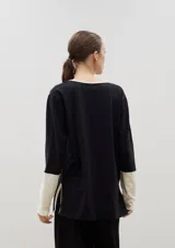 Remera de algodón con escote en V, manga larga y diseño bicolor. Presenta cuerpo en color beige con detalles en negro en el escote, los puños y los tajos laterales.
