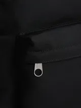 Mochila negra de diseño redondeado con acabado texturizado. Cuenta con un compartimento principal amplio, un bolsillo exterior con cremallera y un bolsillo interior de malla abierto. Tiene asas ajustables y acolchadas, asa superior y un parche tejido con el logo de Tommy Jeans en la parte delantera.