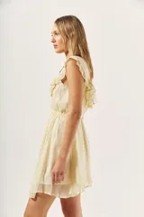 Vestido corto color crema con acabado brillante, escote redondo con volados decorativos en los hombros, cintura elástica y falda acampanada.