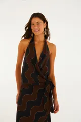 Top de escote halter con diseño cruzado, lazo lateral y estampado geométrico de ondas en tonos negro y marrón con líneas doradas.