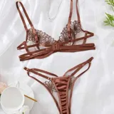 Conjunto de lencería de tul color chocolate con bordado floral, compuesto por un soutiene con aros y tiras cruzadas bajo el busto, y una bombacha colaless con tiras ajustables.