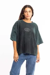 Remera de corte boxy fit, color negro con efecto lavado, de manga corta y cuello redondo. Presenta un logo bordado en el centro del pecho dentro de un óvalo.