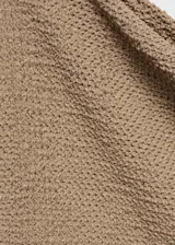 Camiseta de punto color beige con cuello asimétrico y manga larga.
