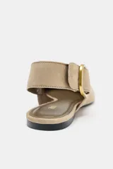 Zapato plano destalonado color beige, de serraje, con punta fina y tira trasera con hebilla metálica.