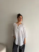 Blusa de viscosa con estampado de lunares, corte holgado, mangas tres cuartos y escote en V con botón central.