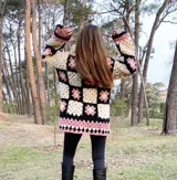 Tapado tejido a mano en crochet con lana hilada y teñida a mano. Diseño con cuadrados de colores blanco, negro y rosa con motivos florales. Cierre con botones.