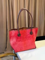 Bolso shopper de cuero azul con textura crocco, manijas largas marrones y costuras artesanales visibles en los bordes.