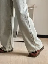 Jean wide leg de tiro alto y pierna ancha, confeccionado en denim de color celeste claro con acabado desgastado. Cuenta con diseño clásico de cinco bolsillos y cierre frontal con botón y cremallera.
