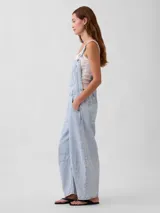 Mono enterito de denim celeste con diseño de rayas verticales blancas, corte holgado tipo horseshoe, tirantes ajustables y bolsillos frontales.