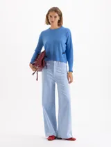 Sweater de tejido de punto en color gris, con cuello redondo, mangas largas y detalle de bordado amarillo en el puño y en el lateral inferior. Presenta un corte recto y estructura ligera.