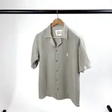 Camisa de manga corta color verde seco, confeccionada en muselina con cuello cubano y cierre frontal con botones.