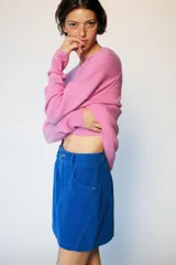Falda mini de pana azul, con diseño de cinco bolsillos, cierre frontal con cremallera y botón.