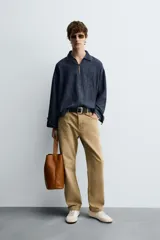 Camisa de manga larga, corte relajado, confeccionada en tejido de mezcla de algodón y lino con efecto lavado. Presenta cuello solapa y abertura frontal con cierre parcial.