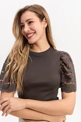 Remera color tostado con cuerpo acanalado y mangas cortas abullonadas con bordados calados.
