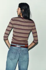 Jersey de punto fino con diseño a rayas horizontales en tonos tierra, bordó y celeste. Presenta cuello redondo, cierre frontal con botones y mangas por debajo del codo.