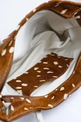 Cartera acolchada negra de silueta ovalada con asa circular integrada y diseño matelassé en rombos.
