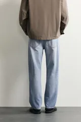 Pantalón de jean corte slim fit con efecto lavado, tiro medio, cinco bolsillos y cierre frontal con cremallera y botón.