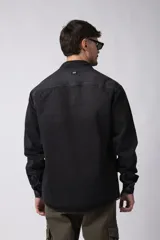 Chaqueta de denim celeste de corte relajado, con cuello clásico, cierre frontal con botones metálicos y un bolsillo aplicado en el pecho.