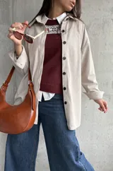 Sobrecamisa de pana color natural, con corte oversize, cuello camisero, cierre frontal de botones oscuros y mangas largas con puños abotonados.