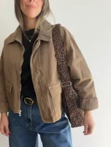 Bolso tipo hobo con estampado animal print y acabado efecto gamuza. Cuenta con asa regulable y cierre superior con cremallera.