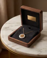 Collar de acero con baño de oro, compuesto por una cadena fina y un dije circular que presenta un árbol de la vida dorado en el centro, enmarcado por un borde de cerámica blanca.