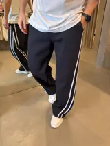 Pantalón deportivo de corte baggy y estilo oversize, color negro con doble franja lateral blanca. Confeccionado en algodón premium, cuenta con bolsillos laterales y cintura elástica.