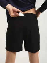 Short deportivo tipo runner color negro, confeccionado en tejido técnico de secado rápido. Presenta un corte corto, cintura elástica y logo reflectante en la pierna derecha.