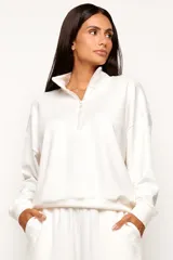 Buzo de viscosa color blanco marfil con cuello alto y cierre frontal parcial, de manga larga y diseño levemente oversize.
