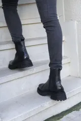 Bota corta de cuero color marrón con suela track negra y cierre lateral con cremallera.