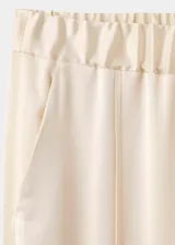 Pantalón de corte recto y tiro medio, confeccionado en tejido satinado con forro interior. Presenta cintura elástica, dos bolsillos laterales y aberturas en los bajos.