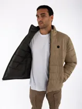Campera puffer reversible color beige con interior negro, cuello alto y cierre frontal con cremallera.
