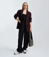 Pantalón de sastrería corte barrel, color negro, con pliegues delanteros y cierre desplazado en la cintura. Diseño de pierna ancha y estructurada.