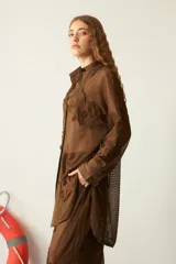 Camisola larga de red marrón, con diseño de tejido a cuadros y apliques florales bordados en relieve por toda la prenda. Presenta cuello camisero y botones frontales.