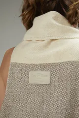 Chaleco sin mangas de lana fina sin teñir, color crudo, con cuello volcado y diseño a cuadros sutil. Presenta terminación a mano en crochet.