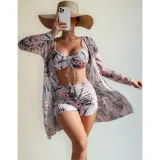Conjunto de traje de baño de tres piezas con estampado de hojas tropicales en tonos blanco y negro. Incluye un top tipo tankini con cordón ajustable en el centro, un short de tiro alto y una camisa abierta de manga larga tipo salida de baño.