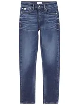 Jeans de hombre de mezclilla azul oscuro con efecto lavado y arrugas marcadas en la parte delantera. Presentan un corte slim, tiro alto, cierre de cremallera y botón, y diseño clásico de cinco bolsillos. Incluyen un parche con logo en la cintura trasera.