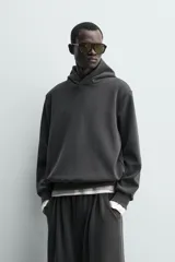 Sudadera tipo hoodie de corte relajado, confeccionada en tejido fluido con efecto lavado. Presenta cuello con capucha, mangas largas y terminaciones en rib.