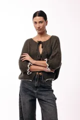 Saco de punto gris con frente abierto, cierre mediante lazos frontales y mangas con puños elásticos. Presenta una textura suave y un diseño de volumen holgado.