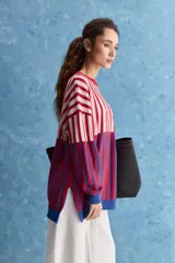 Sweater de tejido jacquard con diseño de rayas verticales en tonos rojo, blanco y azul. Presenta cuello redondo, hombros caídos y puños en contraste de color azul.
