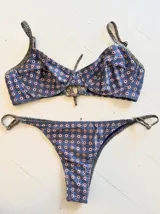 Conjunto de bikini con corpiño con aro y bombacha de atar, con estampado de círculos blancos y rojos sobre fondo azul.