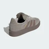 Championes Adidas modelo Samba XLG, con diseño de silueta rediseñada con mayor profundidad. Presentan exterior de cuero y gamuza en tonos gris y marrón, con las icónicas tres tiras laterales y suela de caucho robusta. Incluyen lengüeta acolchada y detalles en dorado.