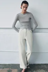 Top de punto fino y semitransparente color gris claro, con cuello redondo y manga larga.